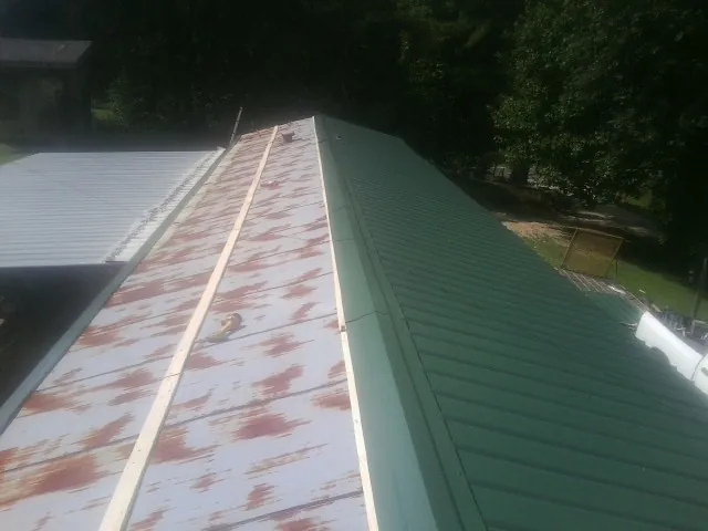 Old rusted panels beside newly installed green metal roofing — Wind Damage Roof Repair by Roofing Brothers in Hamilton